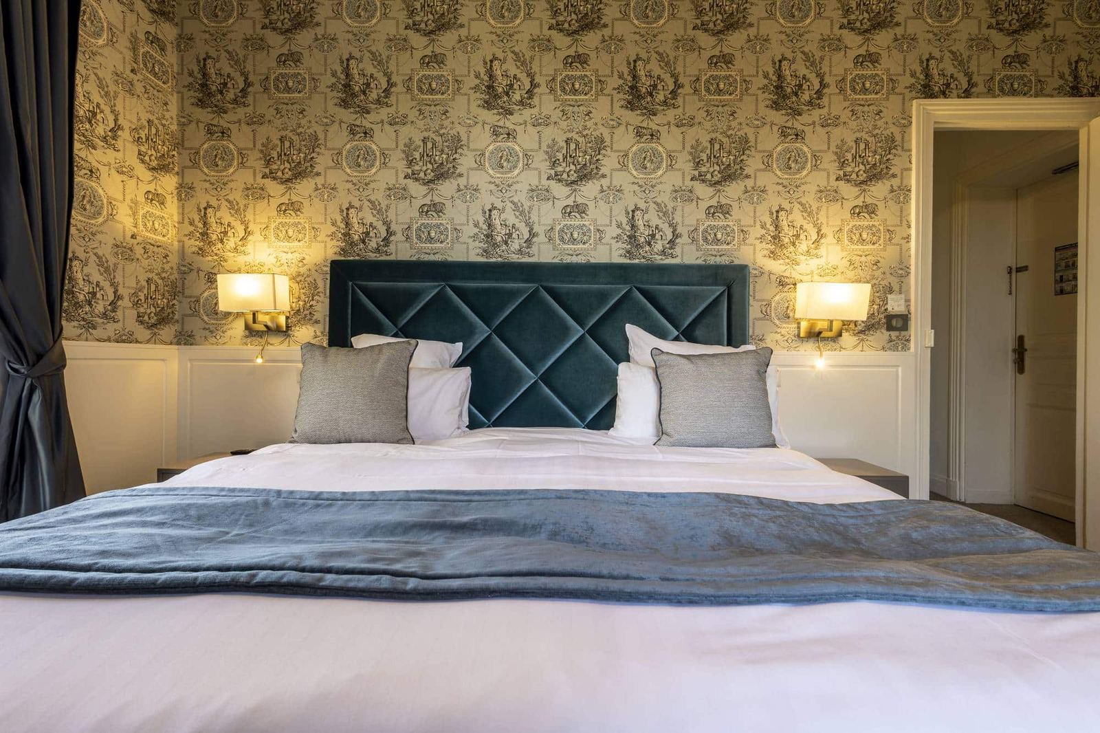 Chambre Bleue : tête de lit capitonnée bleu canard, plaid bleu et appliques sur toile de Jouy