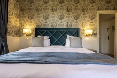 Chambre Bleue : tête de lit capitonnée bleu canard, plaid bleu et appliques sur toile de Jouy