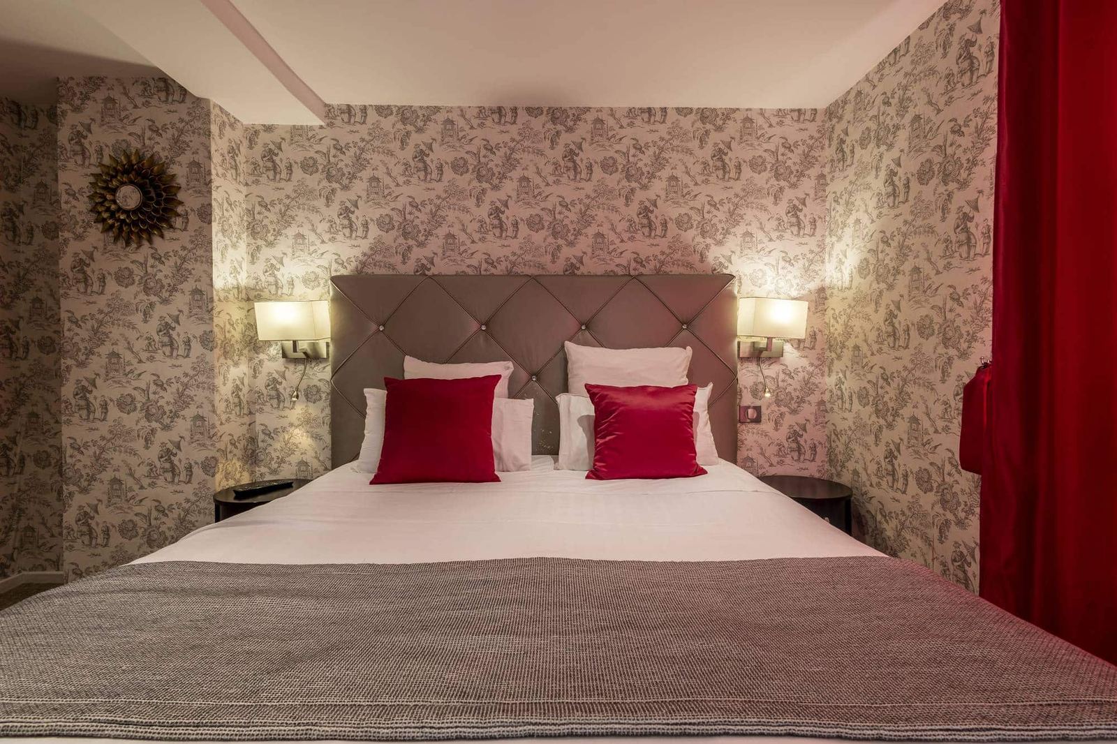 Chambre Coquelicot : tête de lit capitonnée taupe, coussins rouges et papier peint toile de Jouy