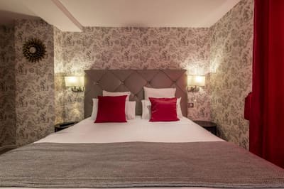 Chambre Coquelicot : tête de lit capitonnée taupe, coussins rouges et papier peint toile de Jouy