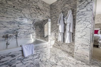 Chambre Coquelicot : baignoire habillée de marbre gris, peignoirs suspendus, chambre en enfilade