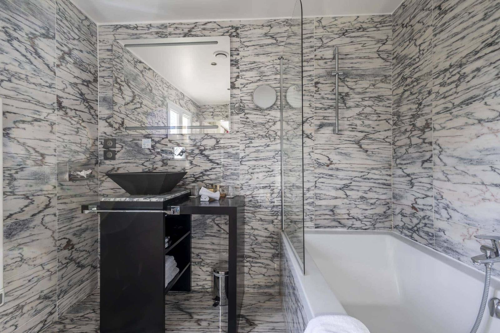 Chambre Coquelicot : salle de bains en marbre veiné, vasque noire et baignoire à paroi vitrée