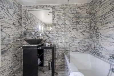Chambre Coquelicot : salle de bains en marbre veiné, vasque noire et baignoire à paroi vitrée