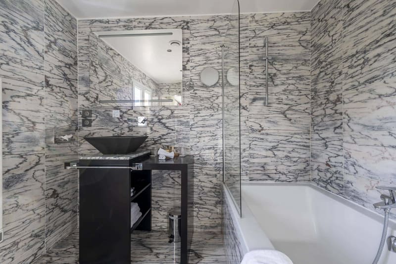 Chambre Coquelicot : salle de bains en marbre veiné, vasque noire et baignoire à paroi vitrée