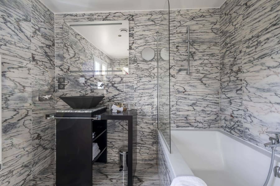 Chambre Coquelicot : salle de bains en marbre veiné, vasque noire et baignoire à paroi vitrée