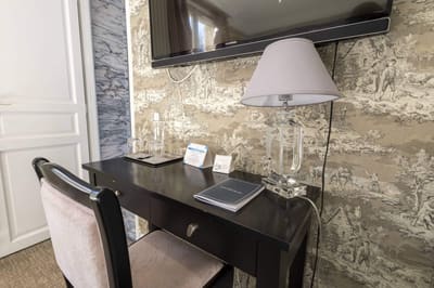 Chambre Coquillage : bureau noir, lampe et téléviseur devant le papier peint toile de Jouy