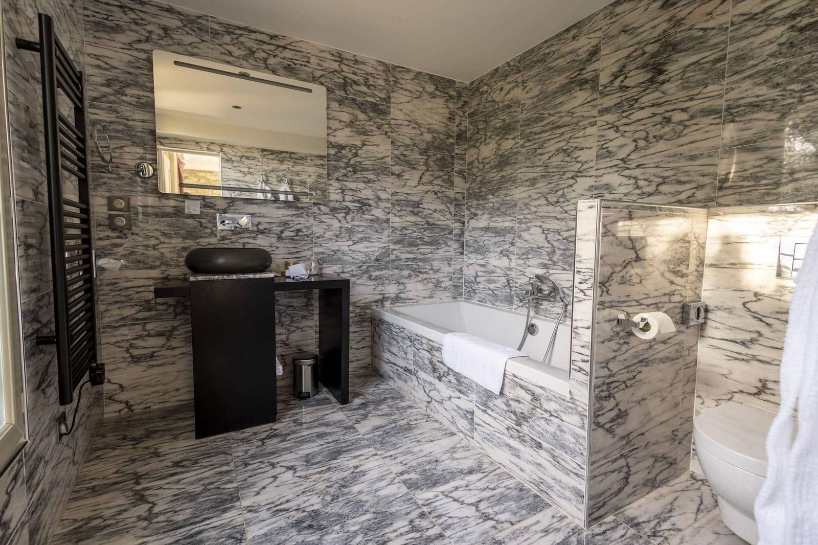 Chambre Coquillage : marbre veiné, vasque noire ronde, baignoire et sèche-serviettes noir