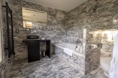 Chambre Coquillage : marbre veiné, vasque noire ronde, baignoire et sèche-serviettes noir