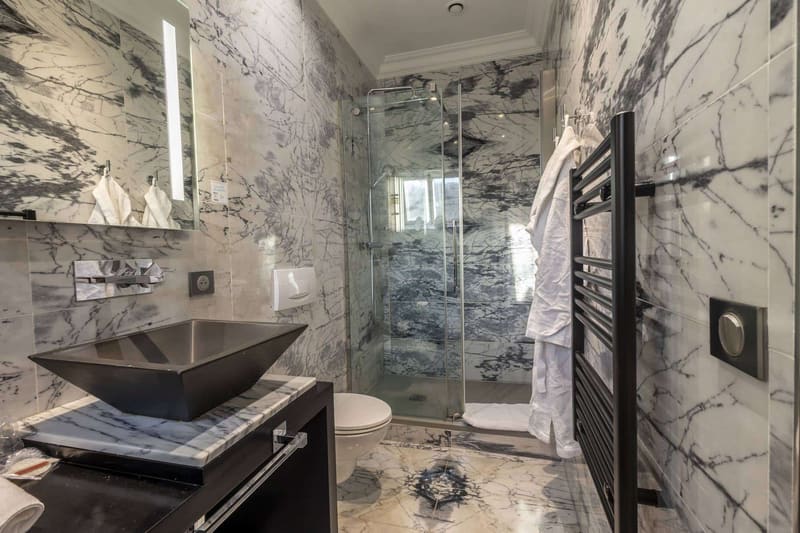 Chambre Dorée : salle de bain en marbre veiné, vasque noire et douche vitrée