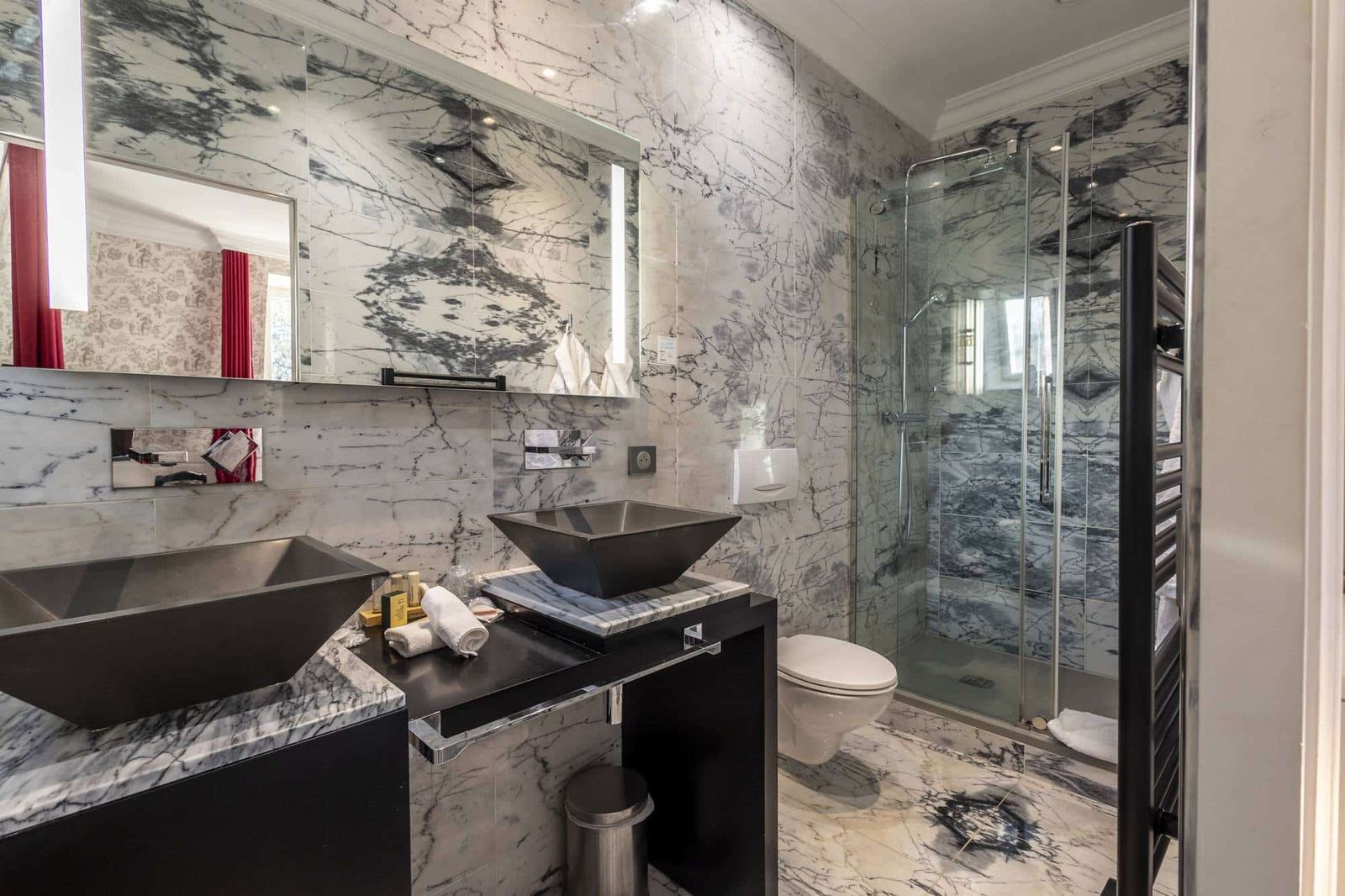 Chambre Dorée : deux vasques noires sous un grand miroir, marbre veiné et douche vitrée