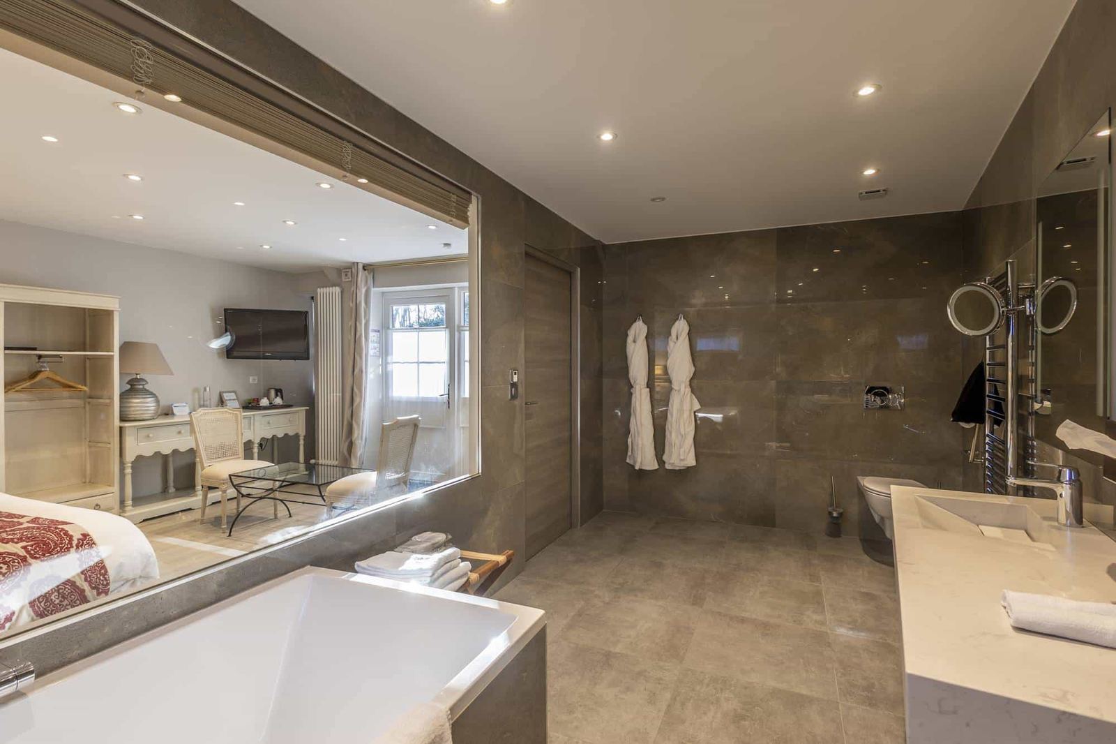 Chambre Centaure : baignoire devant la vitre donnant sur la chambre, peignoirs et vasque claire
