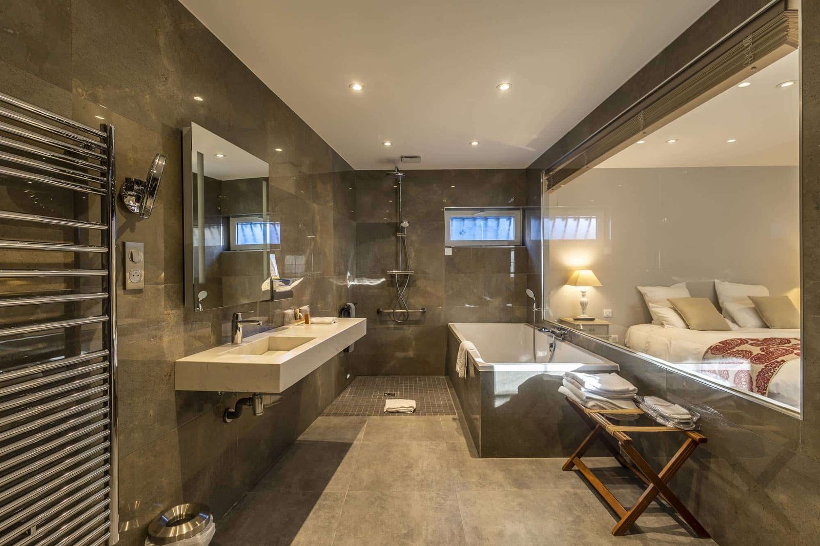 Chambre Centaure : murs sombres, vasque, douche à l’italienne et baignoire ouverte sur le lit