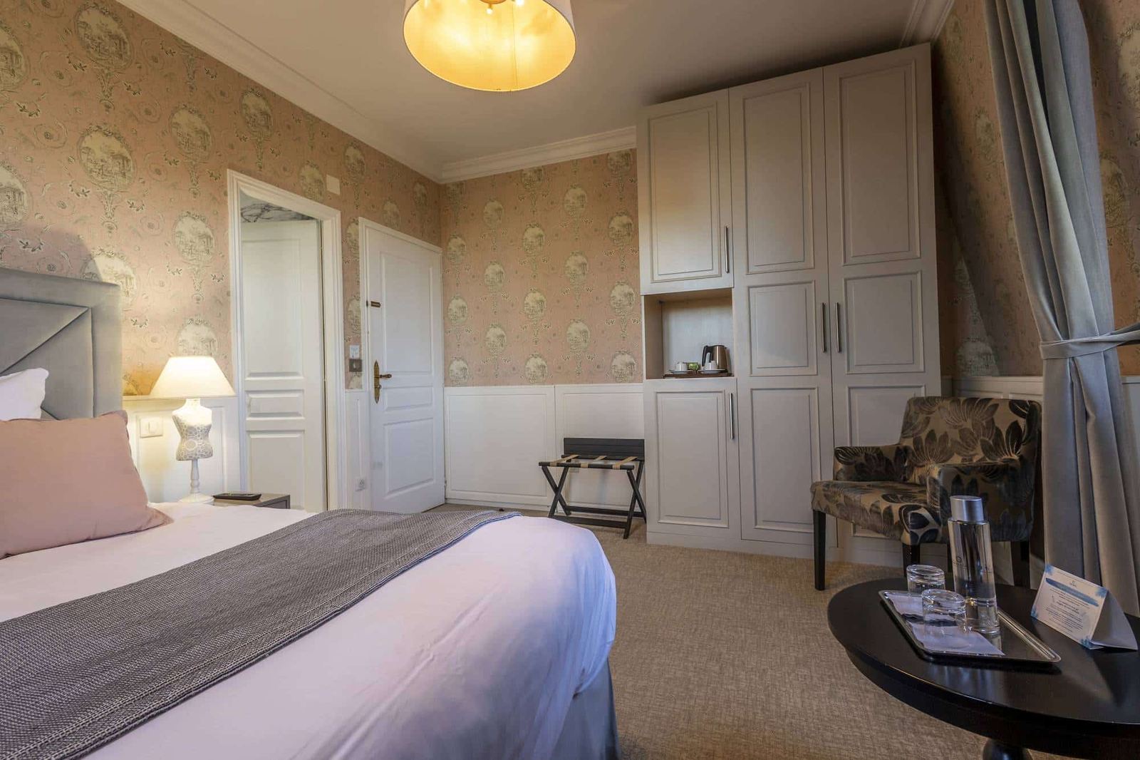 Chambre Romantique : lit, coin bouilloire dans l’armoire, fauteuil fleuri et guéridon à carafe