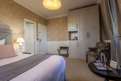 Chambre Romantique : lit, coin bouilloire dans l’armoire, fauteuil fleuri et guéridon à carafe