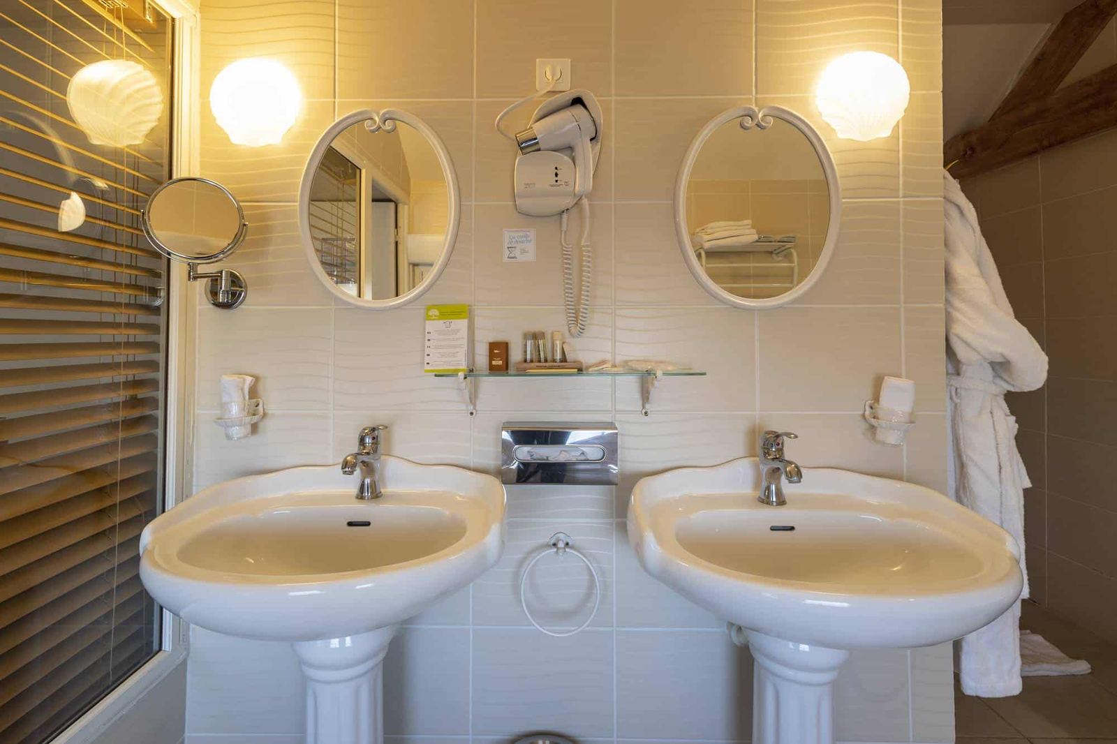 Chambre Voltige : deux lavabos colonne sous miroirs ovales et appliques coquillage