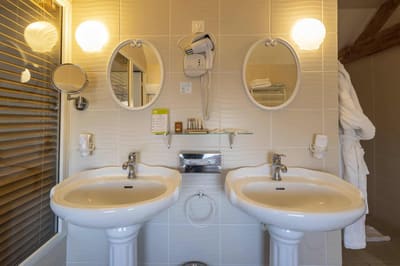 Chambre Voltige : deux lavabos colonne sous miroirs ovales et appliques coquillage