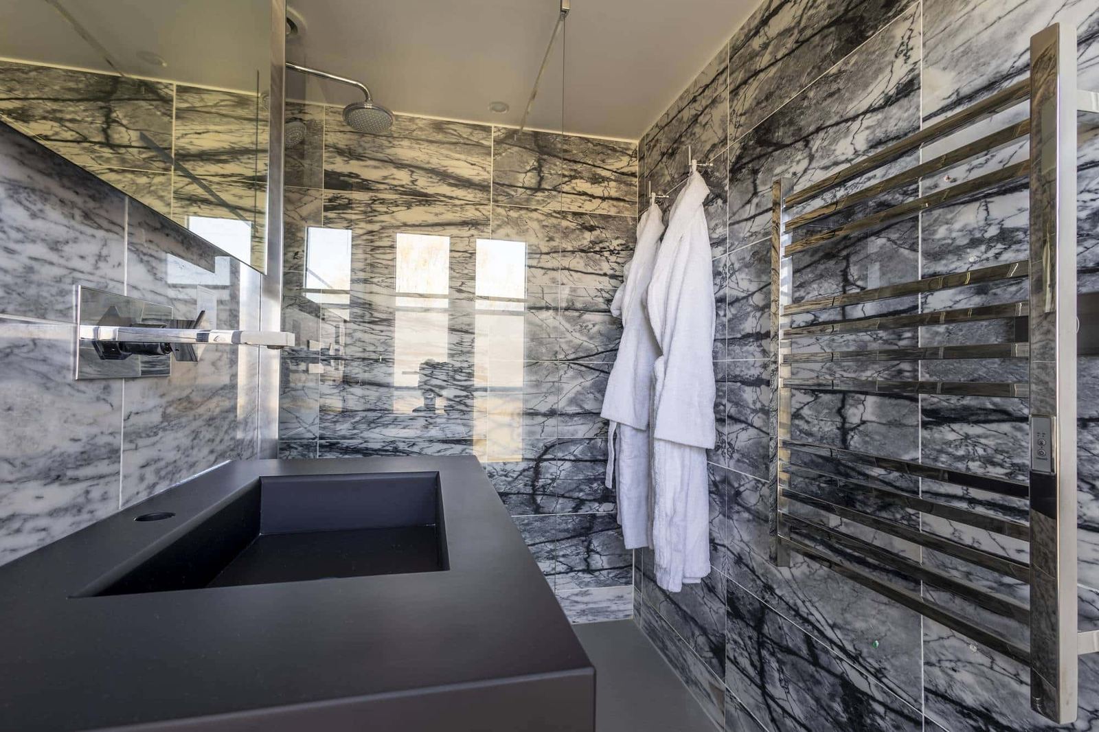 Chambre Vue sur Ferme : vasque noire, douche vitrée, peignoirs et sèche-serviettes chromé sur marbre gris