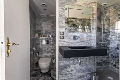 Chambre Vue sur Ferme : salle de bain en marbre gris, vasque noire, douche vitrée et toilettes séparées