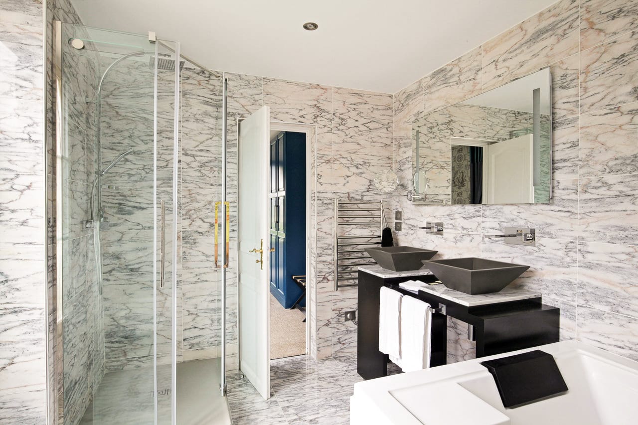 Suite Marquise : douche vitrée, double vasque noire et jacuzzi dans la salle de bains en marbre