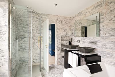 Suite Marquise : douche vitrée, double vasque noire et jacuzzi dans la salle de bains en marbre