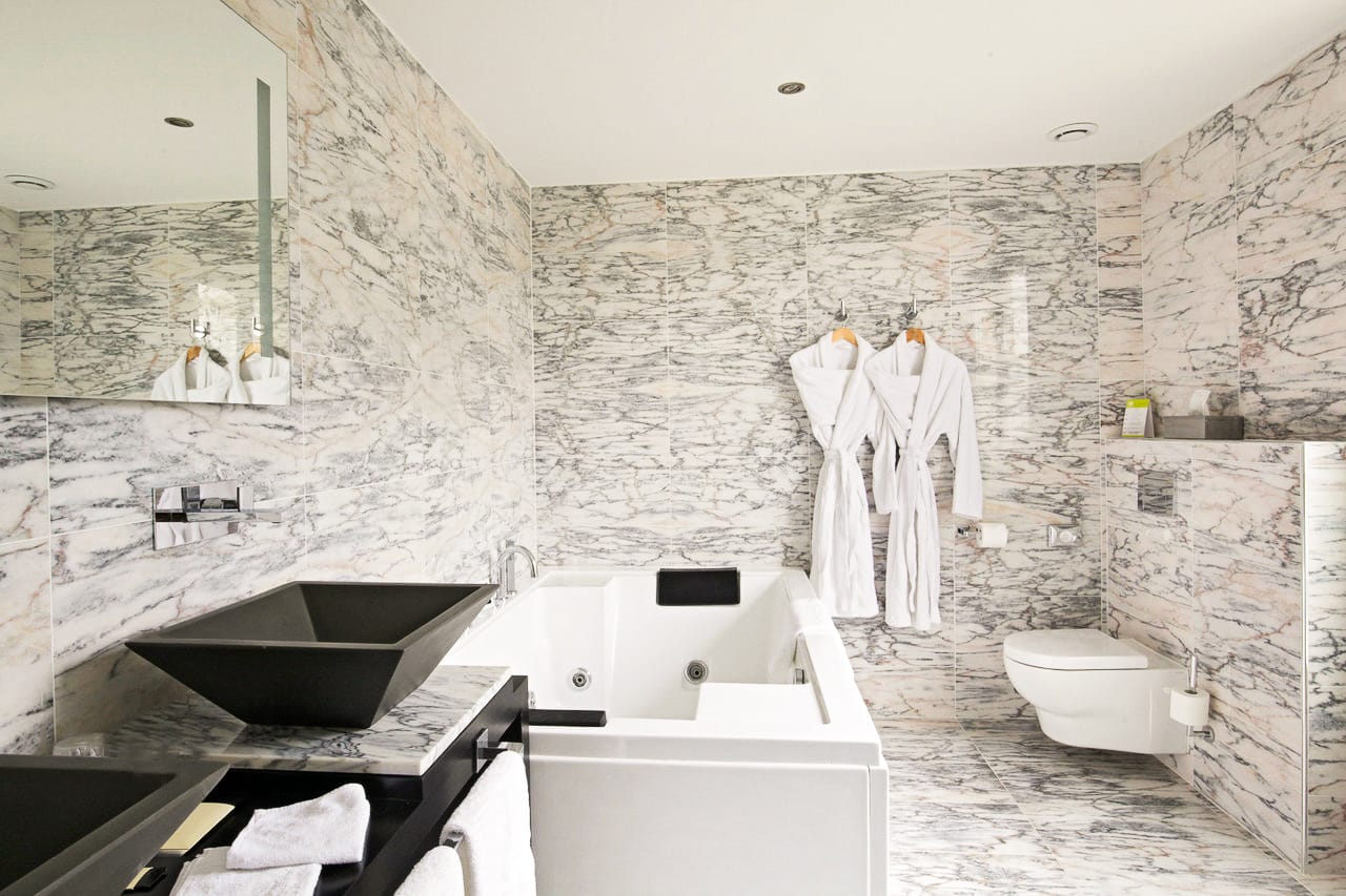 Suite Marquise : jacuzzi, vasque noire et peignoirs blancs dans la salle de bains en marbre