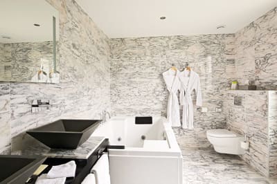 Suite Marquise : jacuzzi, vasque noire et peignoirs blancs dans la salle de bains en marbre