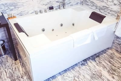 Suite Marquise : jacuzzi à jets et appuie-têtes, sols et murs en marbre veiné de gris
