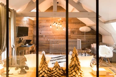 Suite Megève : coin salon et bureau vus à travers la verrière, mur de vieux bois