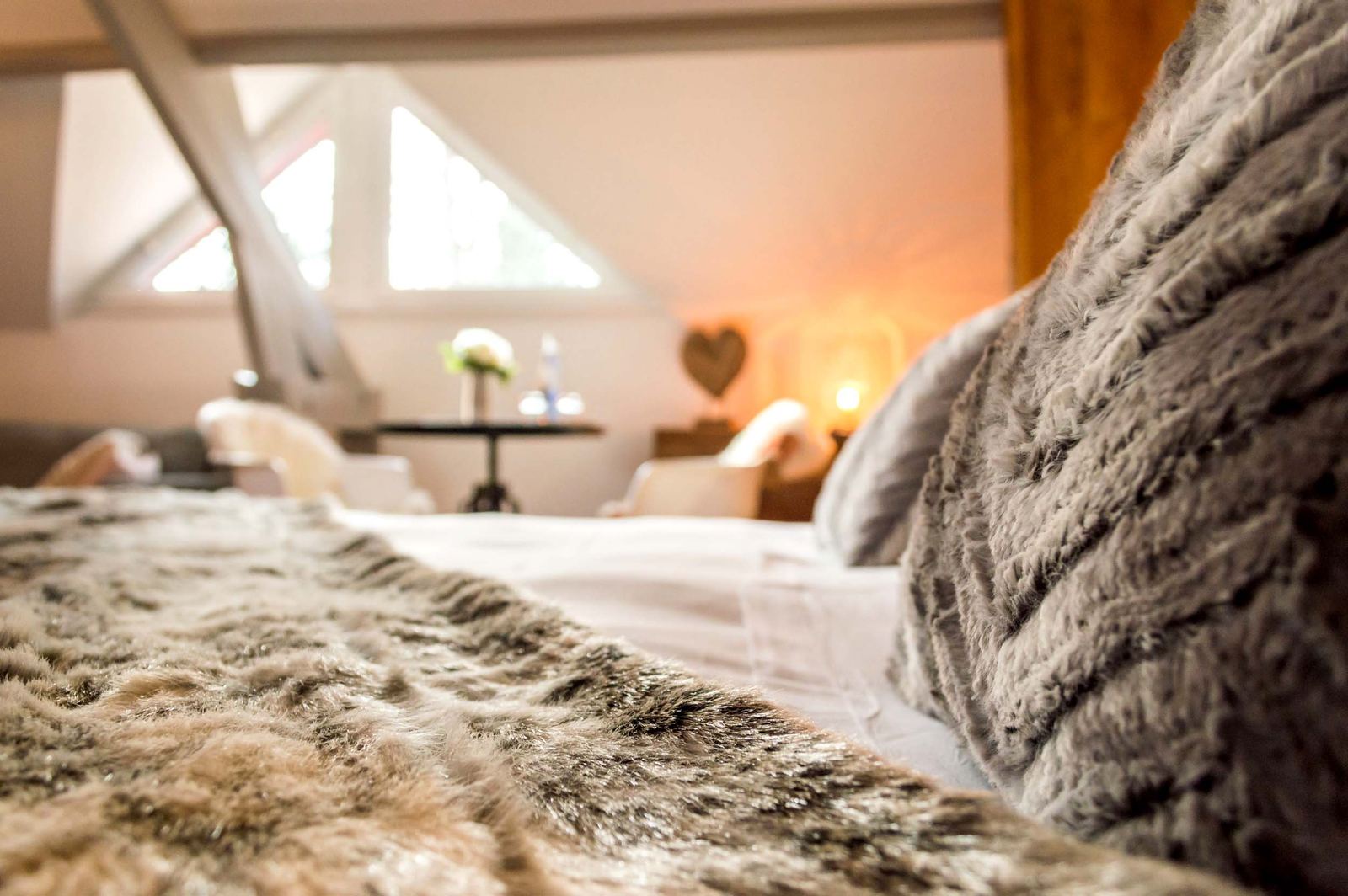Suite Megève : gros plan du plaid fourrure sur le lit, coin salon en arrière-plan