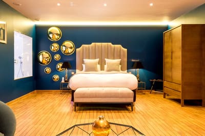 Suite Océan : grand lit à tête capitonnée, murs bleu nuit, miroirs dorés et parquet