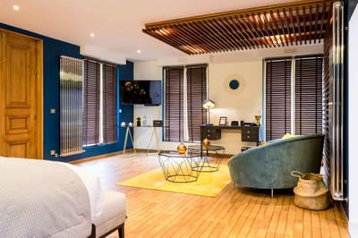 Suite Océan : salon au canapé bleu canard, tapis jaune, bureau et stores de bois