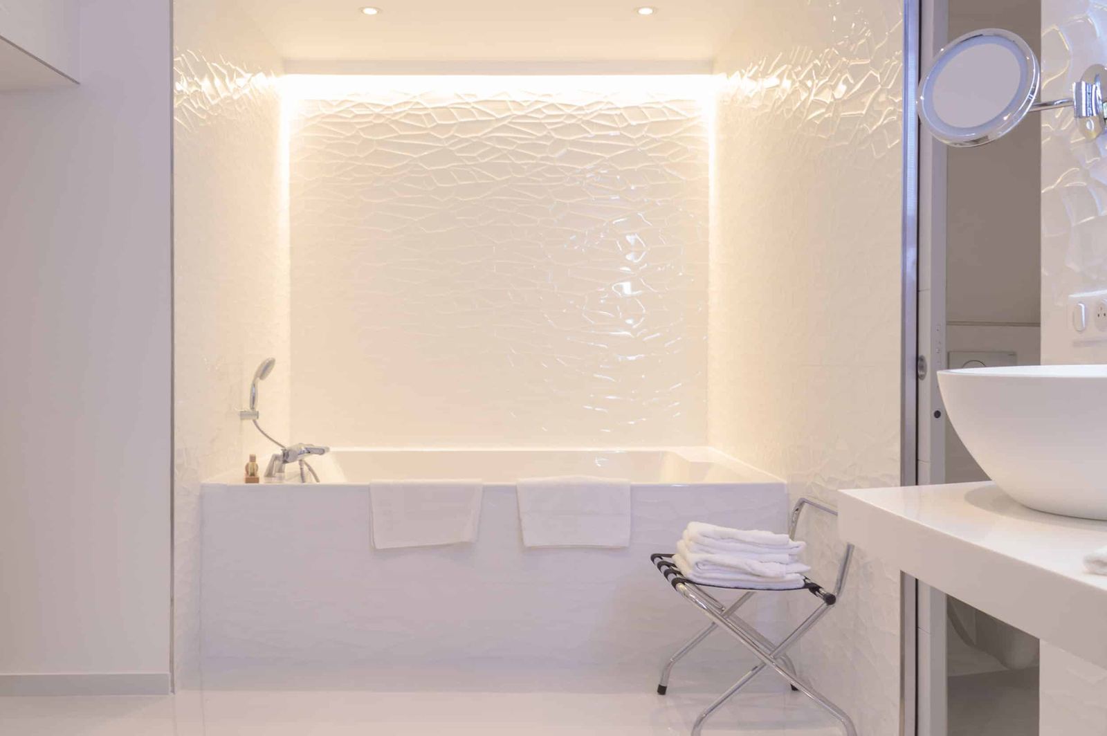 Suite Océan : baignoire encastrée dans une salle de bains blanche au mur en relief