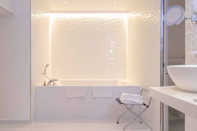 Suite Océan : baignoire encastrée dans une salle de bains blanche au mur en relief