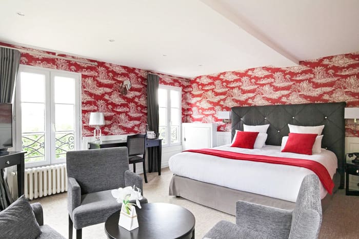 Suite Arlequin : grand lit au plaid rouge, papier peint toile de Jouy et fauteuils gris