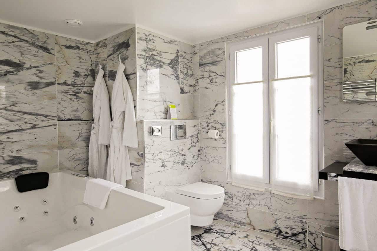 Suite Arlequin : jacuzzi et peignoirs blancs dans la salle de bains en marbre veiné