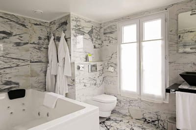 Suite Arlequin : jacuzzi et peignoirs blancs dans la salle de bains en marbre veiné