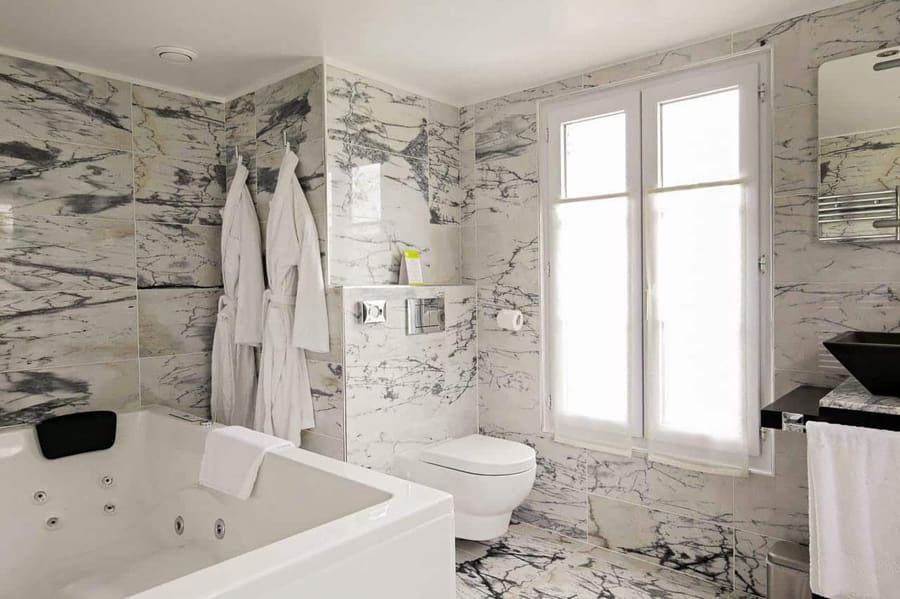 Suite Arlequin : jacuzzi et peignoirs blancs dans la salle de bains en marbre veiné