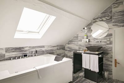 Suite Vue sur Ciel : jacuzzi sous la fenêtre de toit, vasque noire et carrelage marbré gris