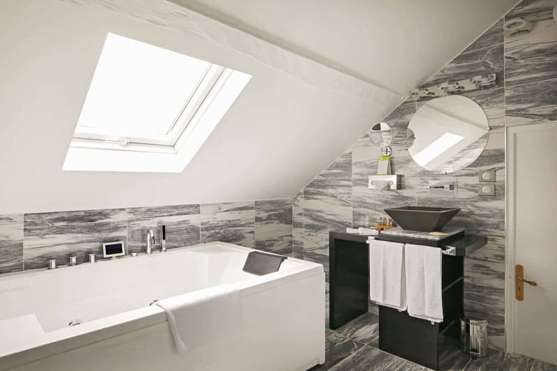Suite Vue sur Ciel : jacuzzi sous la fenêtre de toit, vasque noire et carrelage marbré gris
