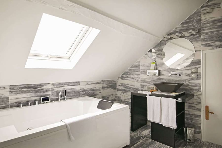 Suite Vue sur Ciel : jacuzzi sous la fenêtre de toit, vasque noire et carrelage marbré gris
