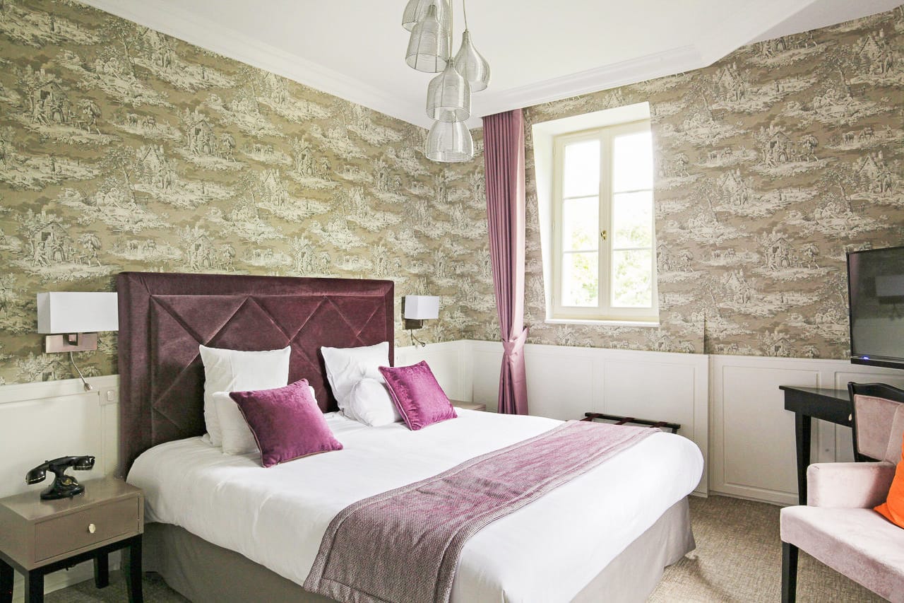 Suite Royale : tête de lit en velours prune, coussins violets, toile de Jouy et fenêtre