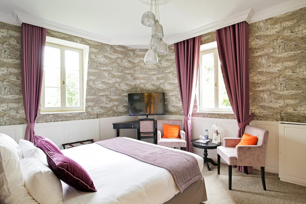 Suite Royale : chambre à la toile de Jouy, rideaux mauves, deux fenêtres et fauteuils roses