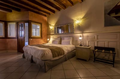 Suite Familiale Licorne : grand lit sous poutres, murs ocre et boiseries, luminaires en grappe