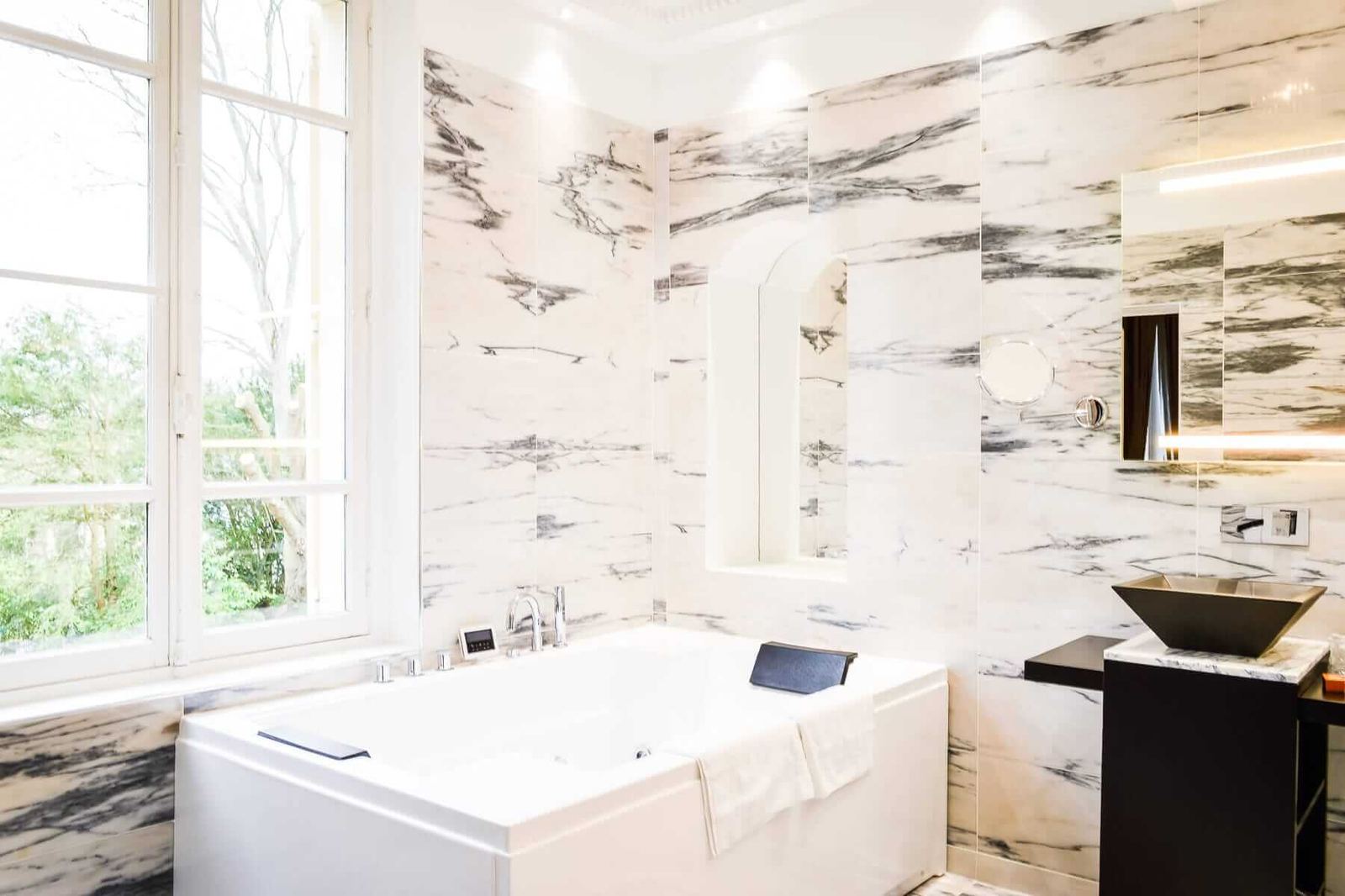 Suite Princière : salle de bains en marbre, jacuzzi sous la fenêtre et vasque noire