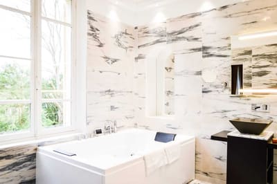 Suite Princière : salle de bains en marbre, jacuzzi sous la fenêtre et vasque noire