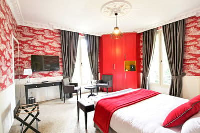 Suite Princière : chambre rouge et blanche, armoire rouge, lit et coin salon entre deux fenêtres