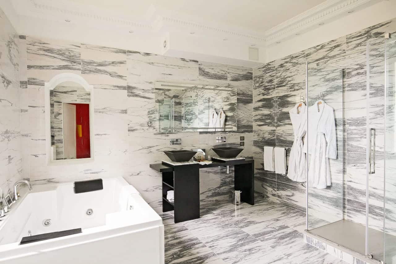 Suite Princière : salle de bains en marbre avec jacuzzi, double vasque noire et douche vitrée